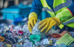 Worker in safety gloves sorting recyclable waste